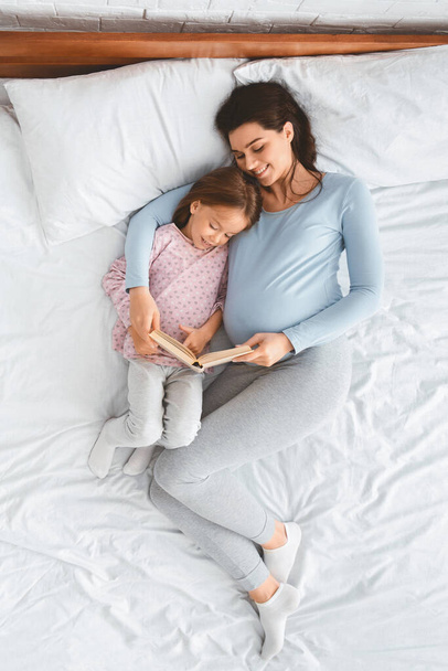 Loving pregnant mom reading book to her little kid - Photo, Image