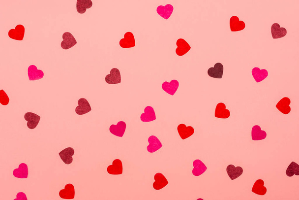 Sevgililer Günü geçmişi. Pembe arka planda kalp şeklinde kağıt konfeti deseni farklı renklerde. Kutlama kompozisyonu. Düz yatış, üst görünüm - Fotoğraf, Görsel
