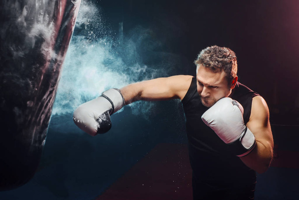 atractivo hombre entrenamiento boxeo en el saco de boxeo - deporte, boxeo y conceptos de entrenamiento - cross boxing
 - Foto, Imagen