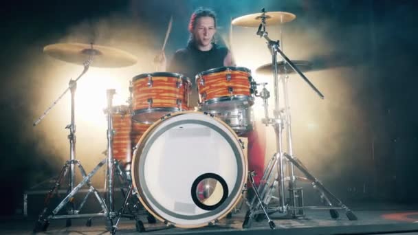 Male Drummer playing drums in smoke. Front view of a man with dreadlocks playing drums - Materiał filmowy, wideo