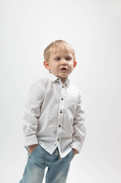 Portrait d'un garçon charismatique élégant et à la mode dans une chemise blanche sur un fond clair raconte quelque chose
. - Photo, image