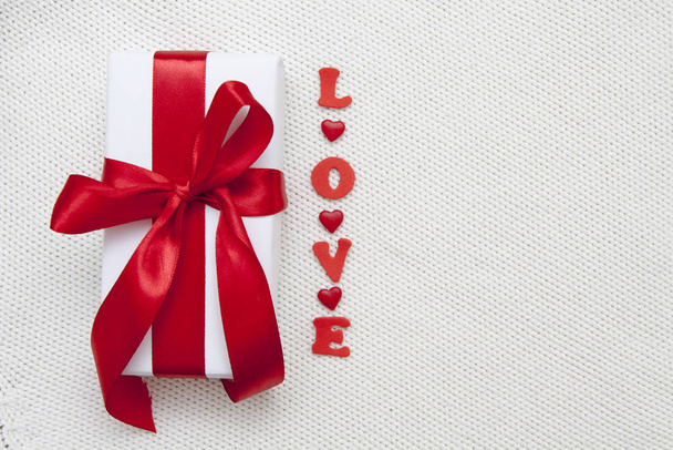 White gift box with a red bow and the word Love flat lay on a wh - Fotó, kép