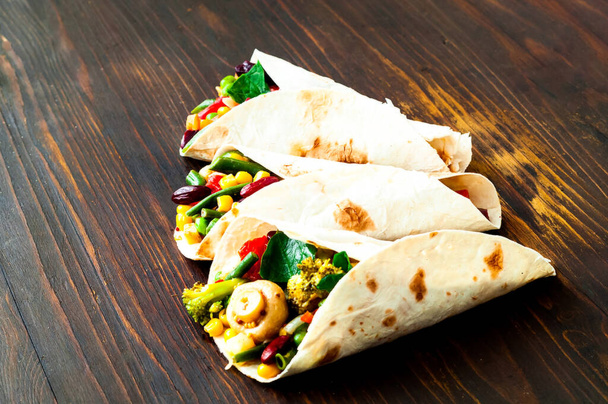 Meksykańska tortilla z nadzieniem warzywnym i grzybowym na drewnianym tle. Idea zdrowego odżywiania. menu przyjazne budżetowi.Close-up - Zdjęcie, obraz