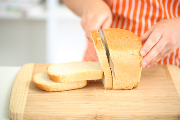 Woman slicing bread on chopping board, close up - Foto, immagini