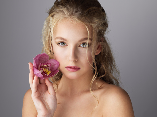 Gri arka planda pembe çiçekli güzel bir kızın portresi - Fotoğraf, Görsel
