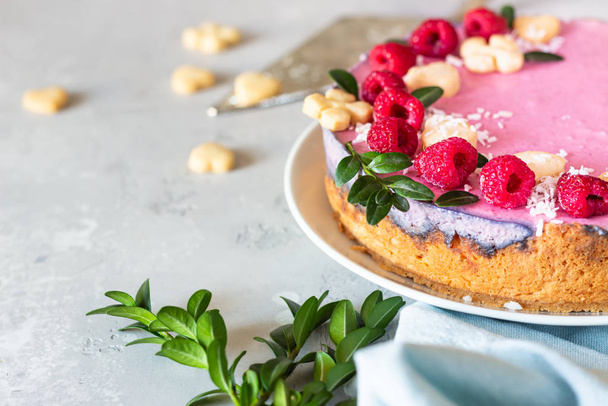 Raspberry cream mousse cake (no baked cheesecake) decorated with fresh raspberries, mini cookies and coconut flakes on light grey background. - Φωτογραφία, εικόνα