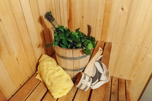 Interior details Finnish sauna steam room bathhouse with traditional sauna accessories basin birch broom scoop felt hat towel - Photo, Image
