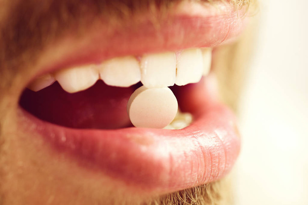 Guys mouth with round pink drug, close up. Medical treatment - Фото, зображення