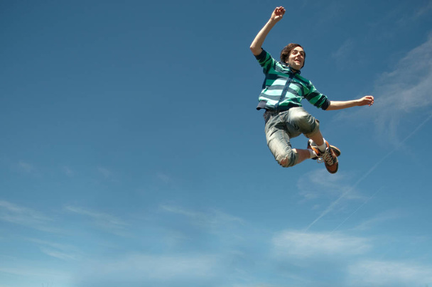 Teen boy jumping blue sky - 写真・画像