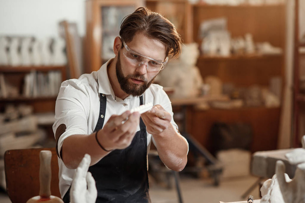 Мужчина гончар глядя на ручной работы колпак в течение рабочего дня в керамике
. - Фото, изображение