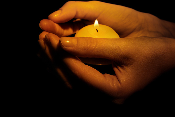 Burning candle in hands isolated on black - Foto, imagen