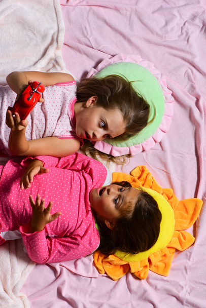 Школьницы в розовой пижаме лежат на красочных подушках, вид сверху
 - Фото, изображение