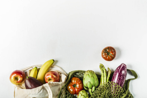 Fresh vegetables in a green string bag and fruit in a bag made o - Fotografie, Obrázek