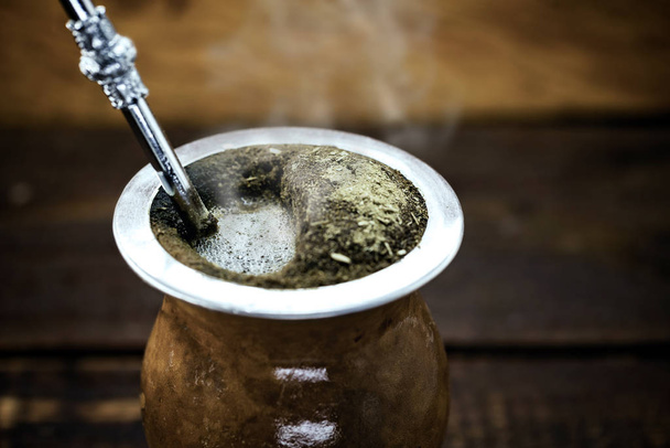 Чай "Ерба мат" в калабаше на деревянном столе. Традиционные аргентинские, уругвайские и бразильские напитки. типичный напиток из rio grande do sul
 - Фото, изображение