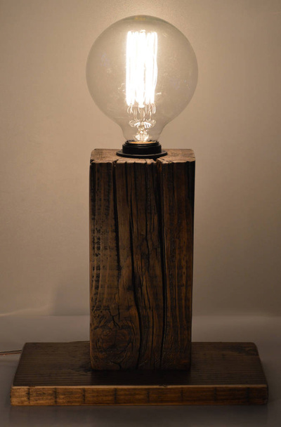 Деревянная лампа ручной работы на сером фоне
 - Фото, изображение