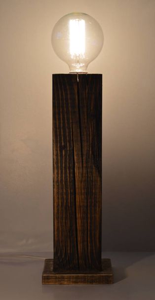 Дерев'яна лампа ручної роботи на сірому фоні
 - Фото, зображення