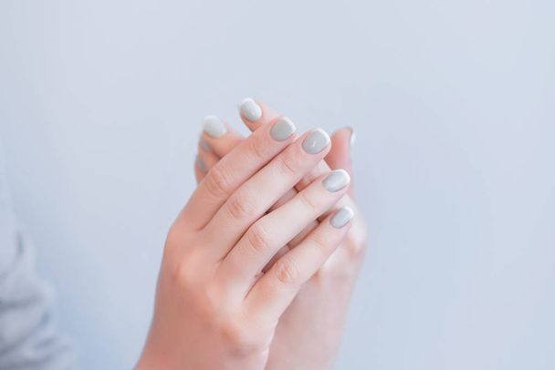 жіночі руки з сірим манікюром на ніжному сірому фоні, долоні на фоні
 - Фото, зображення