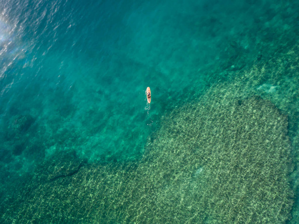 Vista dall'alto verso il basso di un surfista su una tavola da paddle sulla barriera corallina alle Hawaii
 - Foto, immagini