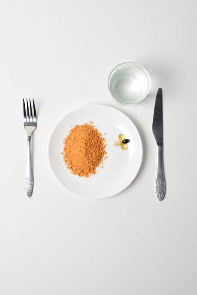 Tomato protein soup powder on a spoon. Hand puts the powder into the glass of water. Meal replacement. Dry soup. Multivitamins, astaxanthin, fish oil, omega pills.  Closeup. - Φωτογραφία, εικόνα