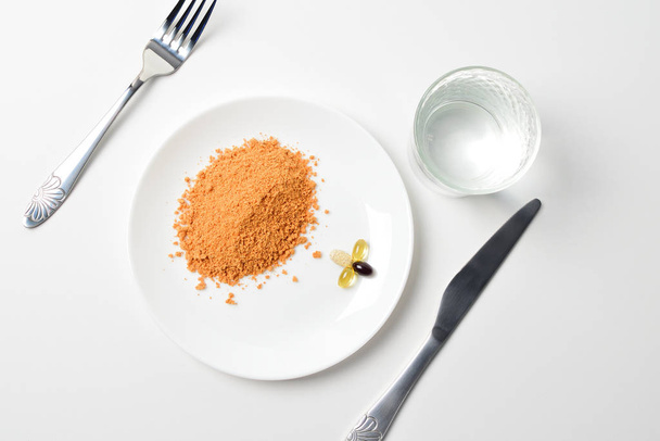 Tomato protein soup powder on a spoon. Hand puts the powder into the glass of water. Meal replacement. Dry soup. Multivitamins, astaxanthin, fish oil, omega pills.  Closeup. - Photo, Image