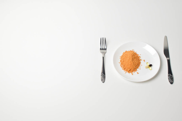 Tomato protein soup powder on a spoon. Hand puts the powder into the glass of water. Meal replacement. Dry soup. Multivitamins, astaxanthin, fish oil, omega pills.  Closeup. - Foto, afbeelding