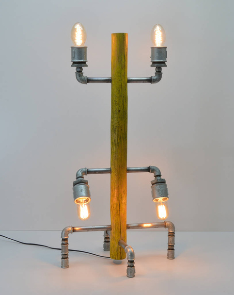 Lámpara artesanal de madera y metal sobre fondo gris
 - Foto, Imagen