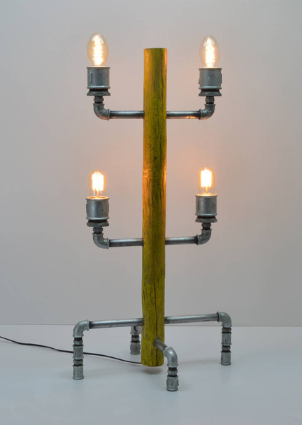 Lámpara artesanal de madera y metal sobre fondo gris
 - Foto, imagen