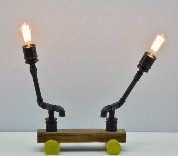 Lampe en bois et métal à la main sur fond gris
 - Photo, image