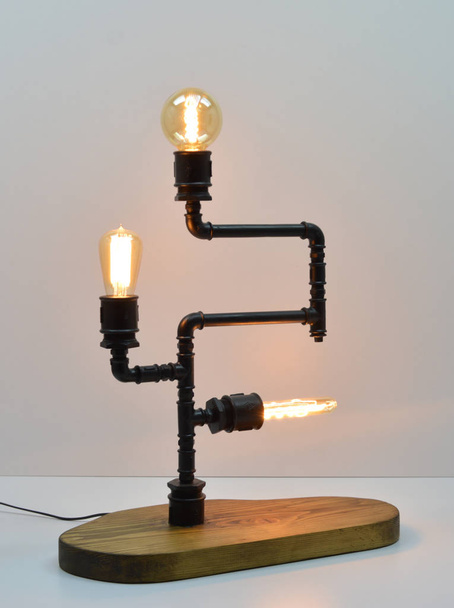 Kézzel készített fa és fém csövek lámpa szürke alapon - Fotó, kép