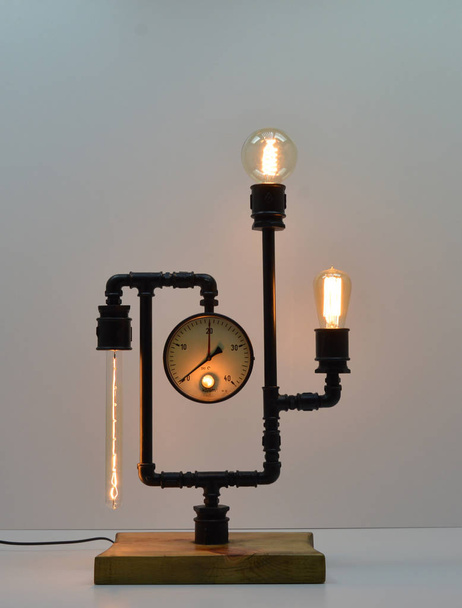 Лампа из дерева и металлических труб ручной работы на сером фоне
 - Фото, изображение