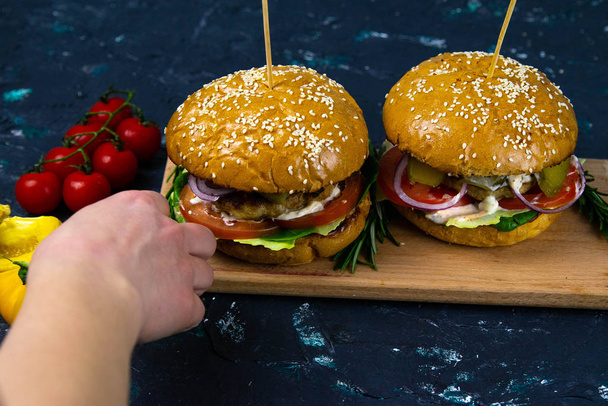 Two homemade beef burgers with mushrooms, micro greens, red onion on wooden cutting board - 写真・画像