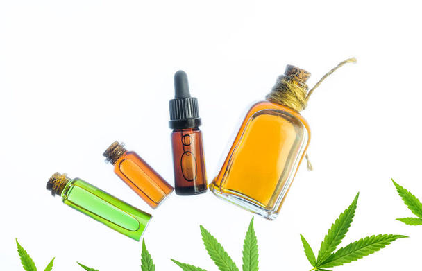 Garrafas de vidro com óleo de Cannabis CBD e tintura de THC e folhas de cânhamo no fundo branco
 - Foto, Imagem