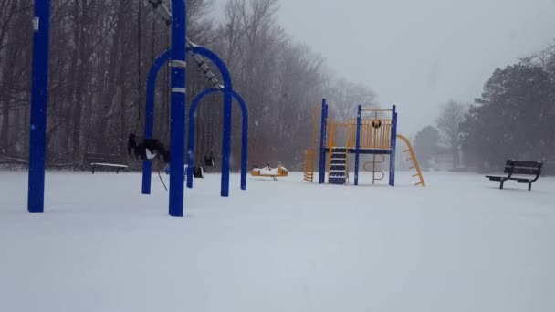 * Светлая версия * Детский игровой парк во время снегопада зимой. Игровая площадка во время снега со снегом на земле в течение дня
. - Кадры, видео