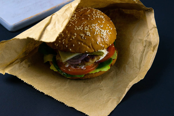 Hamburger auf weißen Verpackungen. alter Holztisch mit Burgern. saftige Salate und warme Semmeln. - Foto, Bild