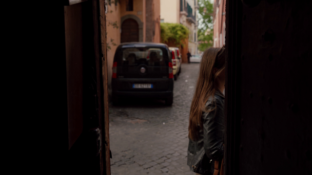 Houkutteleva tyttö kävelee vanhan kaupungin katua oviaukossa sijaitsevan kameran ohi. Trastevere, Rooma, Italia
 - Materiaali, video