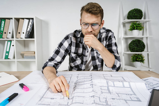 Young adult architect and designer working with blueprints in workspace office - Foto, Imagem