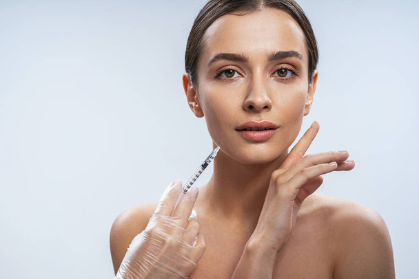 Charming lady is ready for beauty procedures against light background - Foto, Imagen