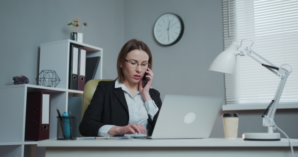 Business Woman in her own Office Talking on the Phone while sitting at the table. Success concept. - Filmagem, Vídeo