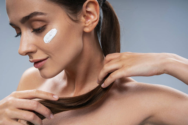 Attractive girl taking care of facial skin against grey background - Fotografie, Obrázek