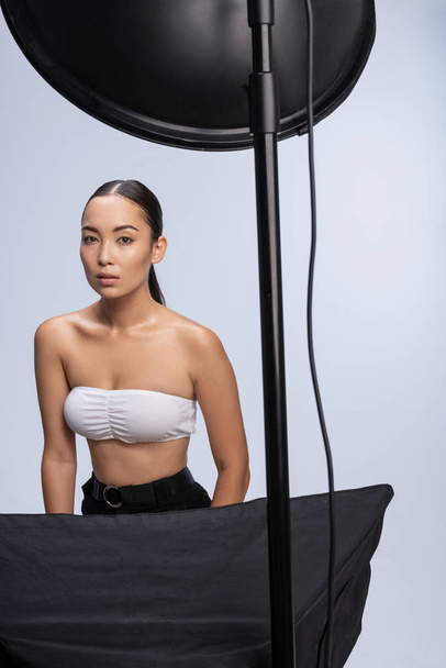 Asian sad woman standing near studio light set - Valokuva, kuva