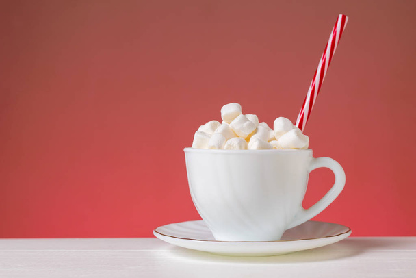 Marshmallow in a white Cup on a white table on a pink background. - Photo, Image