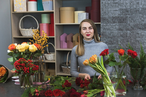 Small business. Male florist unfocused in flower shop. Floral design studio. Cute concentrated young female florist working in flower shop - Photo, Image