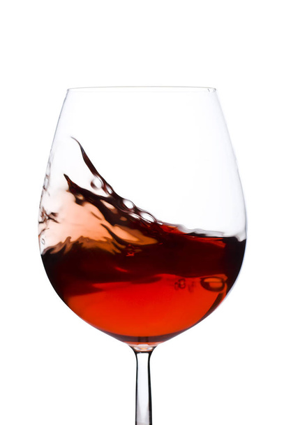 Isolated and moving red wine glass over a white background - Фото, изображение