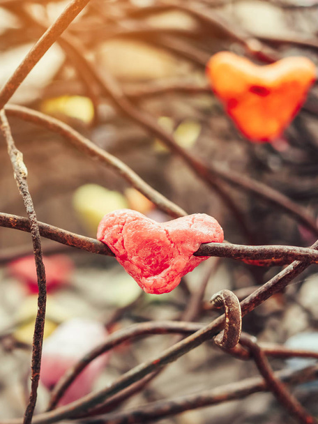 Ένα κομμάτι κόκκινου κεριού σε σχήμα καρδιάς προσκολλάται σε μια παλιά σκουριασμένη ατσάλινη ράβδο. Το φόντο της ημέρας του Αγίου Βαλεντίνου. - Φωτογραφία, εικόνα