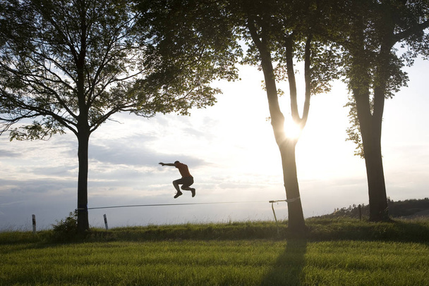 young man on the slackline in the sunset - 写真・画像