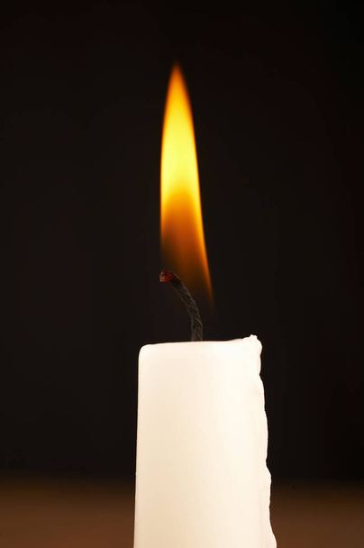 close up of white stick candle with light on black background - Photo, Image