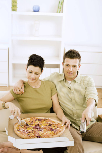 Coppia mangiare pizza e guardare la TV a casa. - Foto, immagini