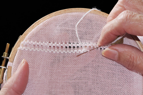 hand holding a needle and a thread on a black background - Φωτογραφία, εικόνα