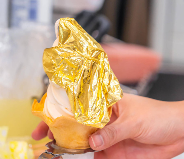 Рука держит золотой лист мороженого подпись мороженое
  - Фото, изображение