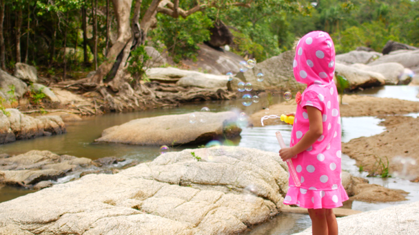 Dívka dítě fouká mýdlové bubliny, mnoho bublin ve větru - Záběry, video